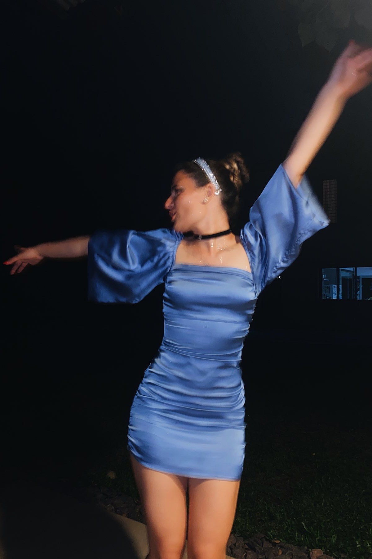 woman in shiny blue dress dances in streeet