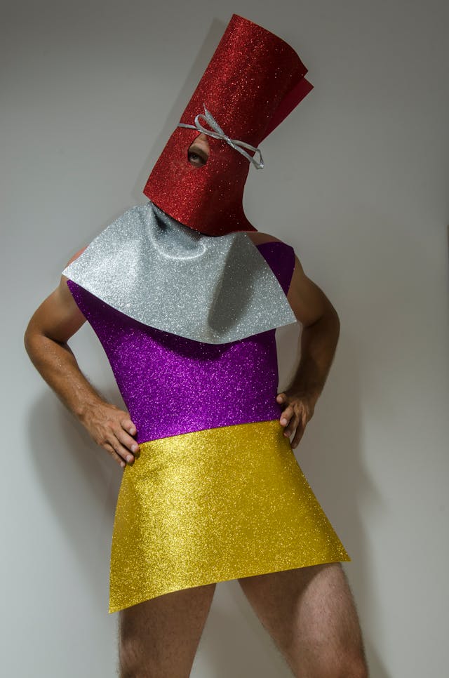 man poses in bright-colored sparlly geometirc outfit