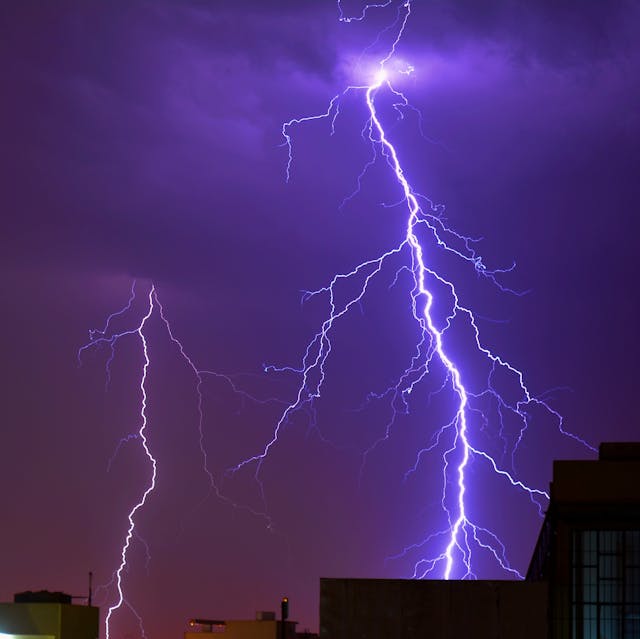 lightning strikes in purple night sky.