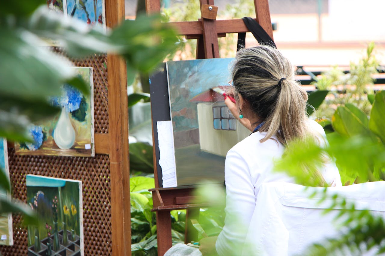 back view of woman painting at easel outdoors